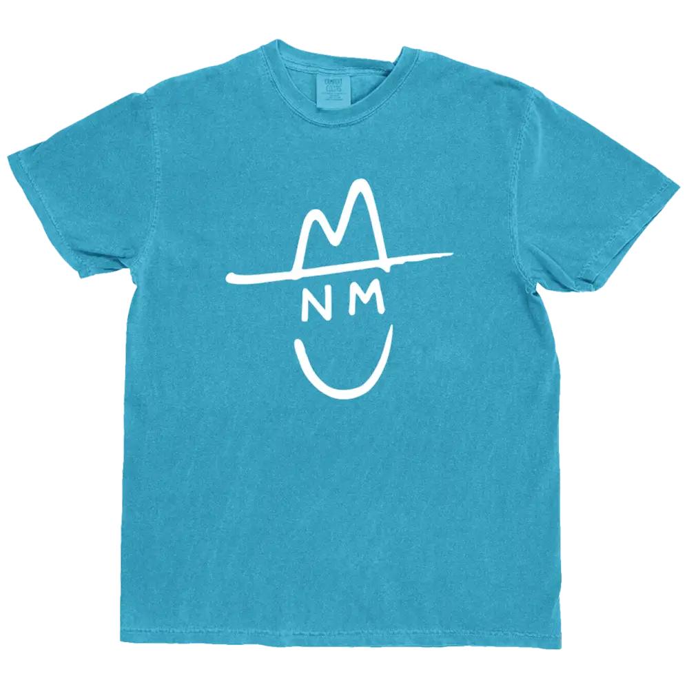 A turquoise cotton t-shirt featuring a white graphic of a smiling face wearing a hat with ’nm’ written across the forehead.