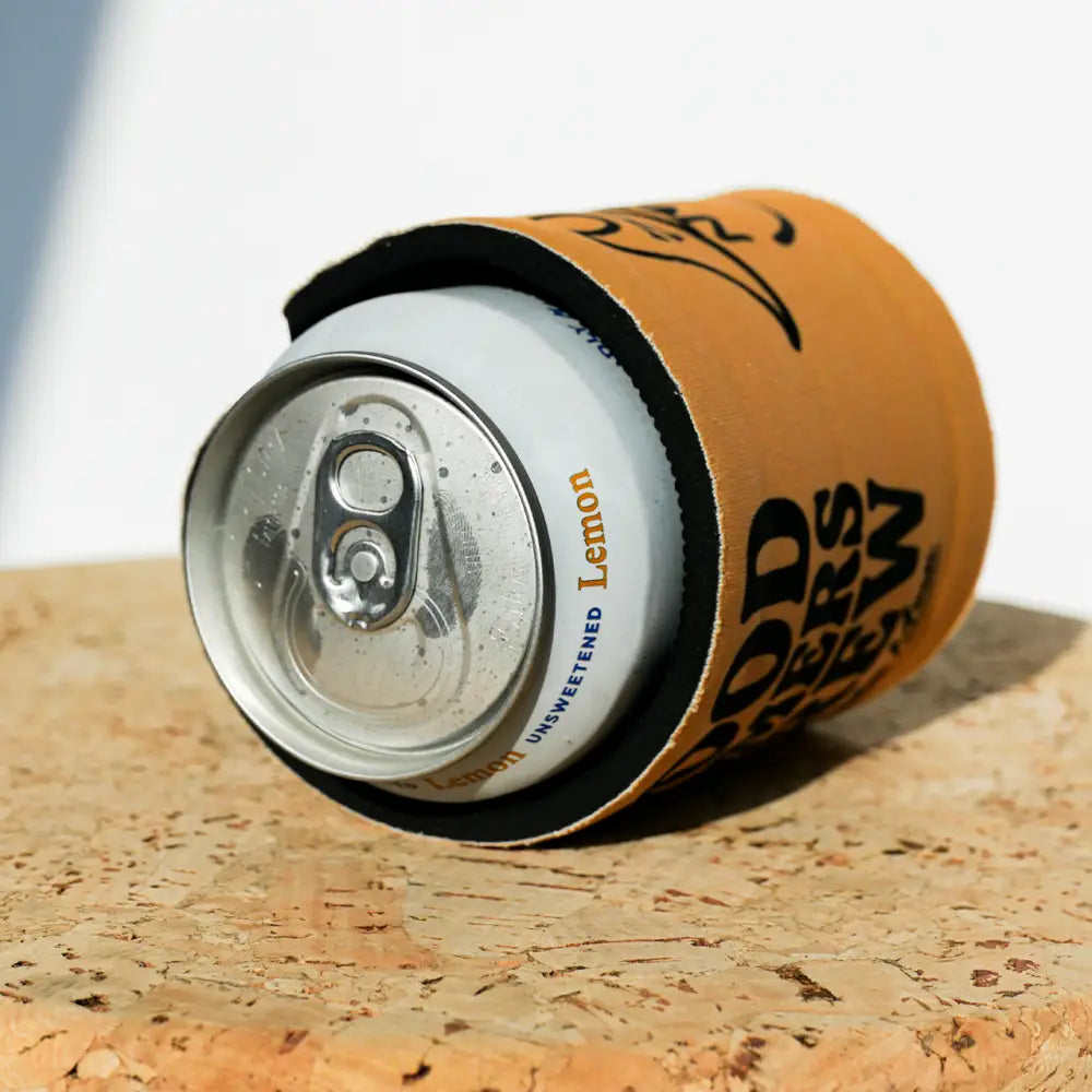 A tan, black-trimmed can cooler snugly wrapped around a silver aluminum soda can.