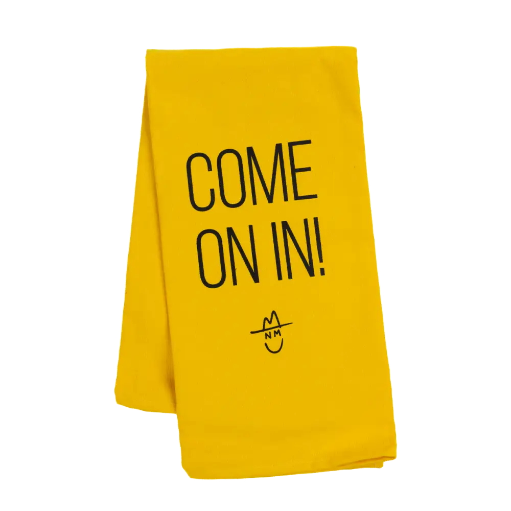 Bright yellow towel or cloth with ’COME ON IN!’ printed in black text and a simple smiley face design.