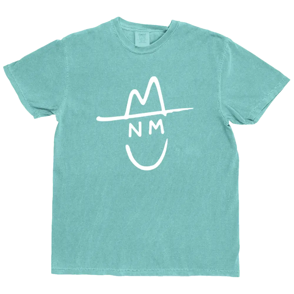 A teal-colored cotton t-shirt featuring a white graphic of a smiling face wearing a hat with ’nm’ written across the forehead.