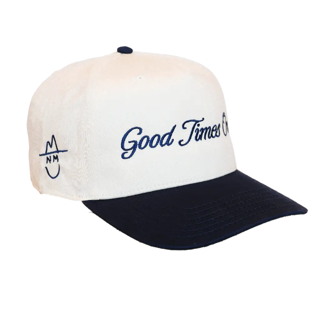 White and navy blue baseball cap with embroidered ’good times on’ in cursive script across the front, featuring a small logo on the left side.