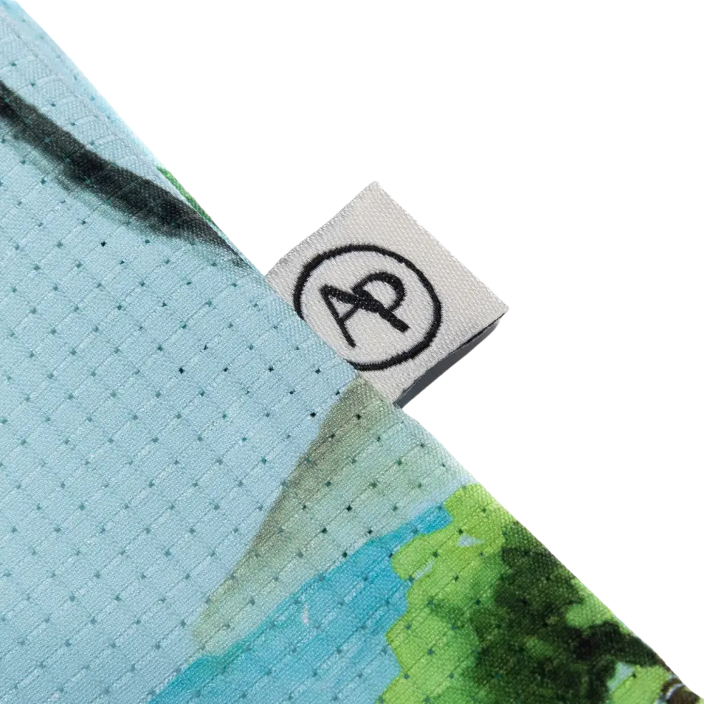 Light blue and green patterned athletic shirt with a white brand tag featuring black ’ap’ logo.