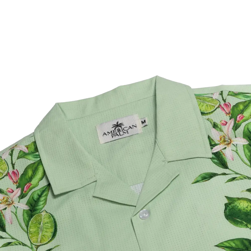 Light green hawaiian shirt with a vibrant citrus and floral pattern, featuring lime slices, pink blossoms, and lush leaves on a subtly textured fabric.